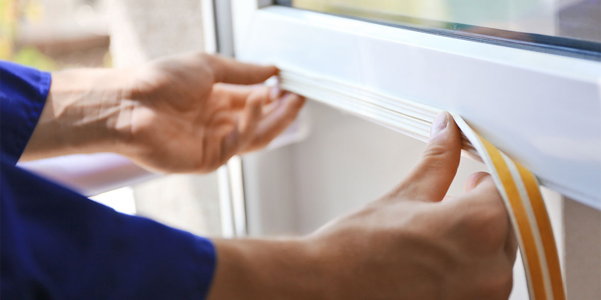 Person draught proofing a window