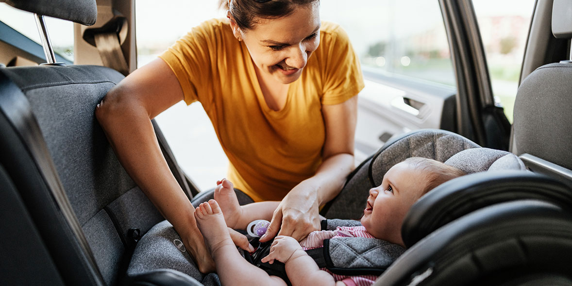 Woman strapping baby into a car seat