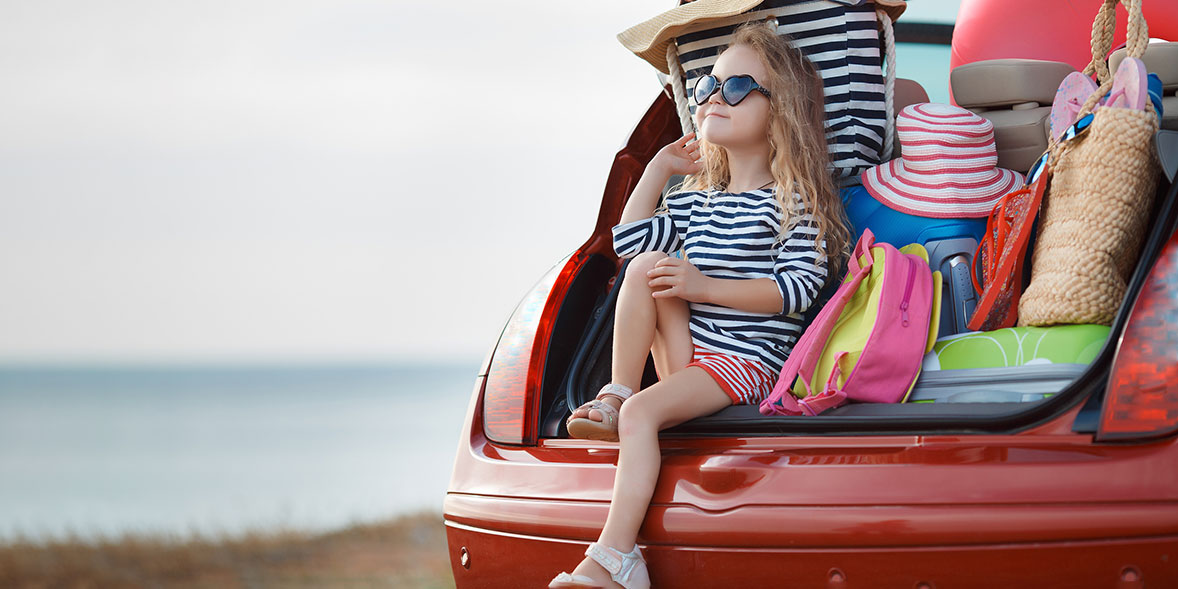 Child sat in car with holiday equipment surrounding her