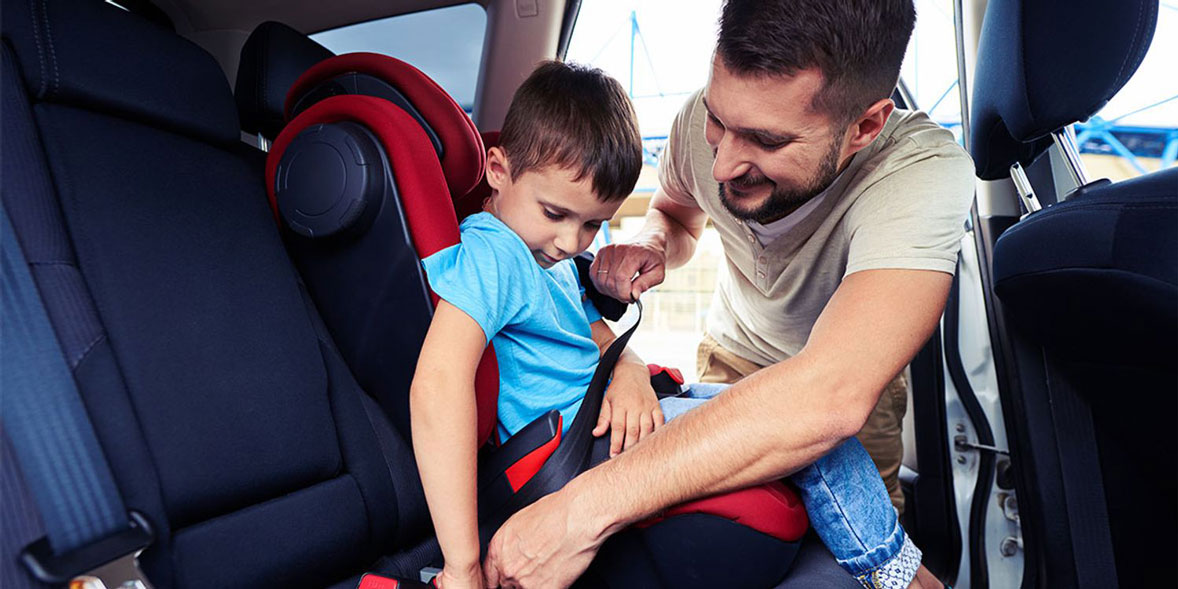 Father strapping son into a high back booster seat