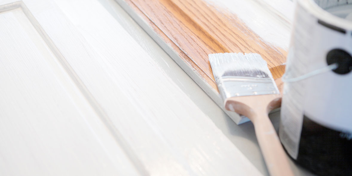 Paint brush with white paint lying on wooden boards