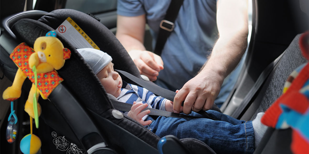 Baby being strapped into a car seat