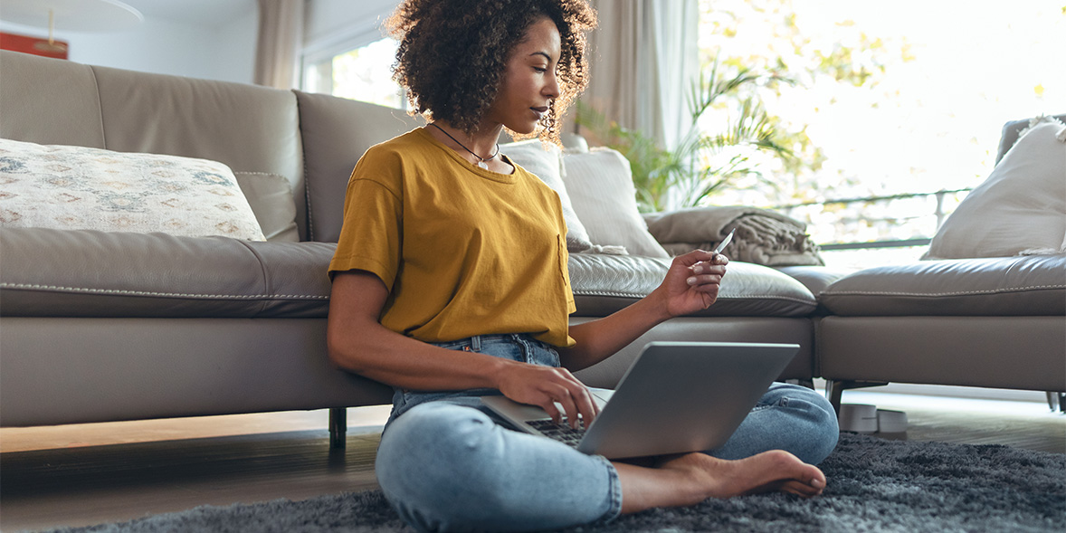 Women looking at card to pay on laptop