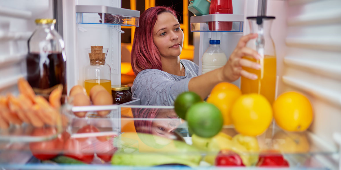 Woman reaching into a fridge freezer